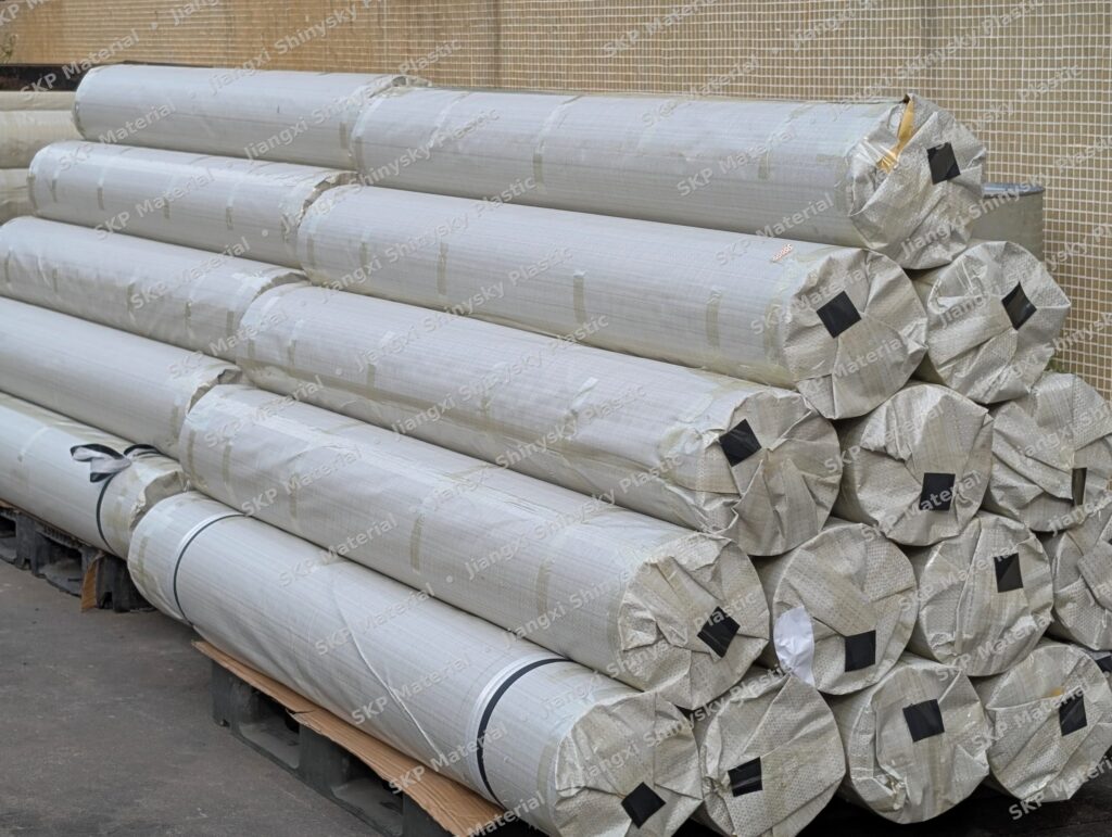 Finished PVC tarpaulin rolls wrapped in woven PP and stacked on pallets in the warehouse