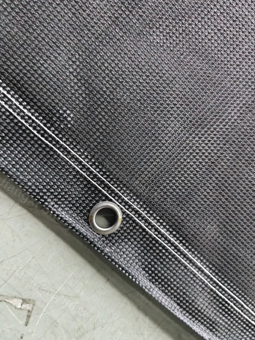 Close-up of a metal eyelet set into the reinforced edge of PVC mesh banner material