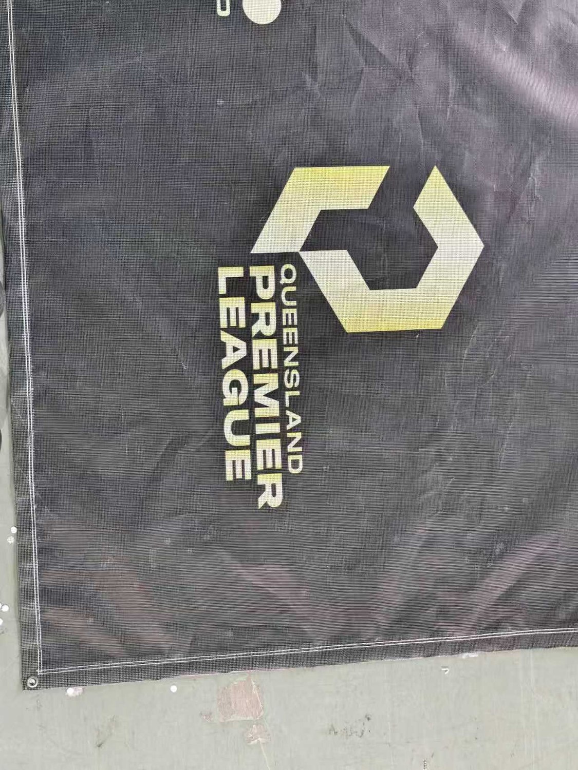 Printed soccer mesh banner with club artwork, hemmed and eyeleted, laid out at the SKP factory