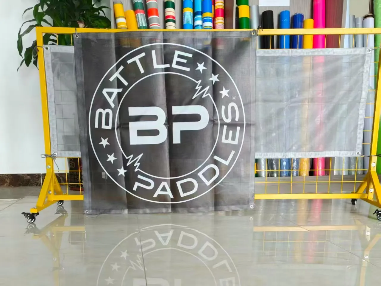 The same printed artwork shown on black mesh banner and on white mesh banner side by side
