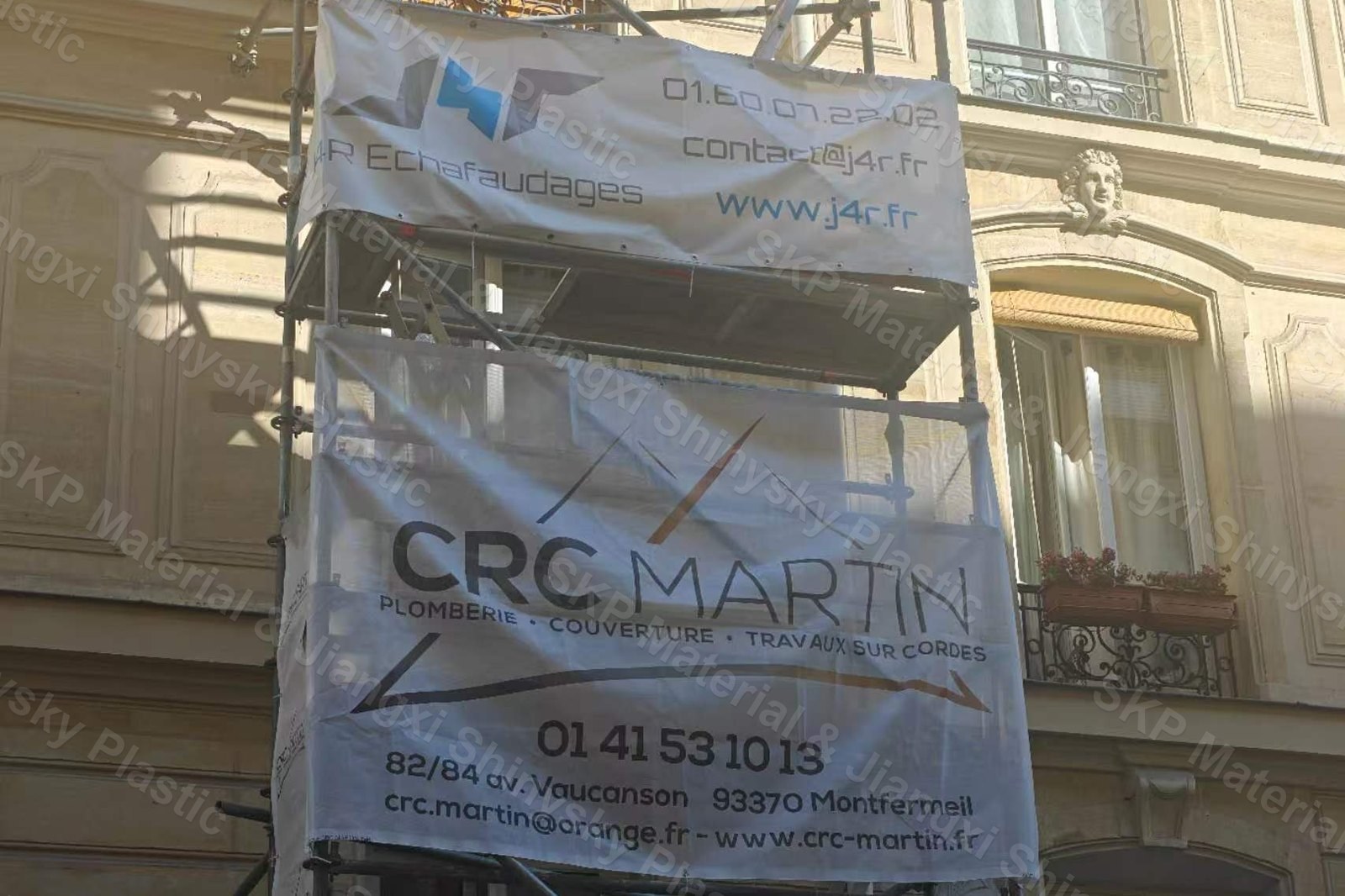 Two printed PVC mesh banners mounted on scaffolding across a building facade