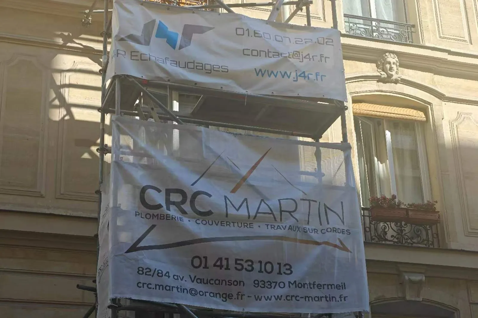 Two printed PVC mesh banners mounted on scaffolding across a building facade